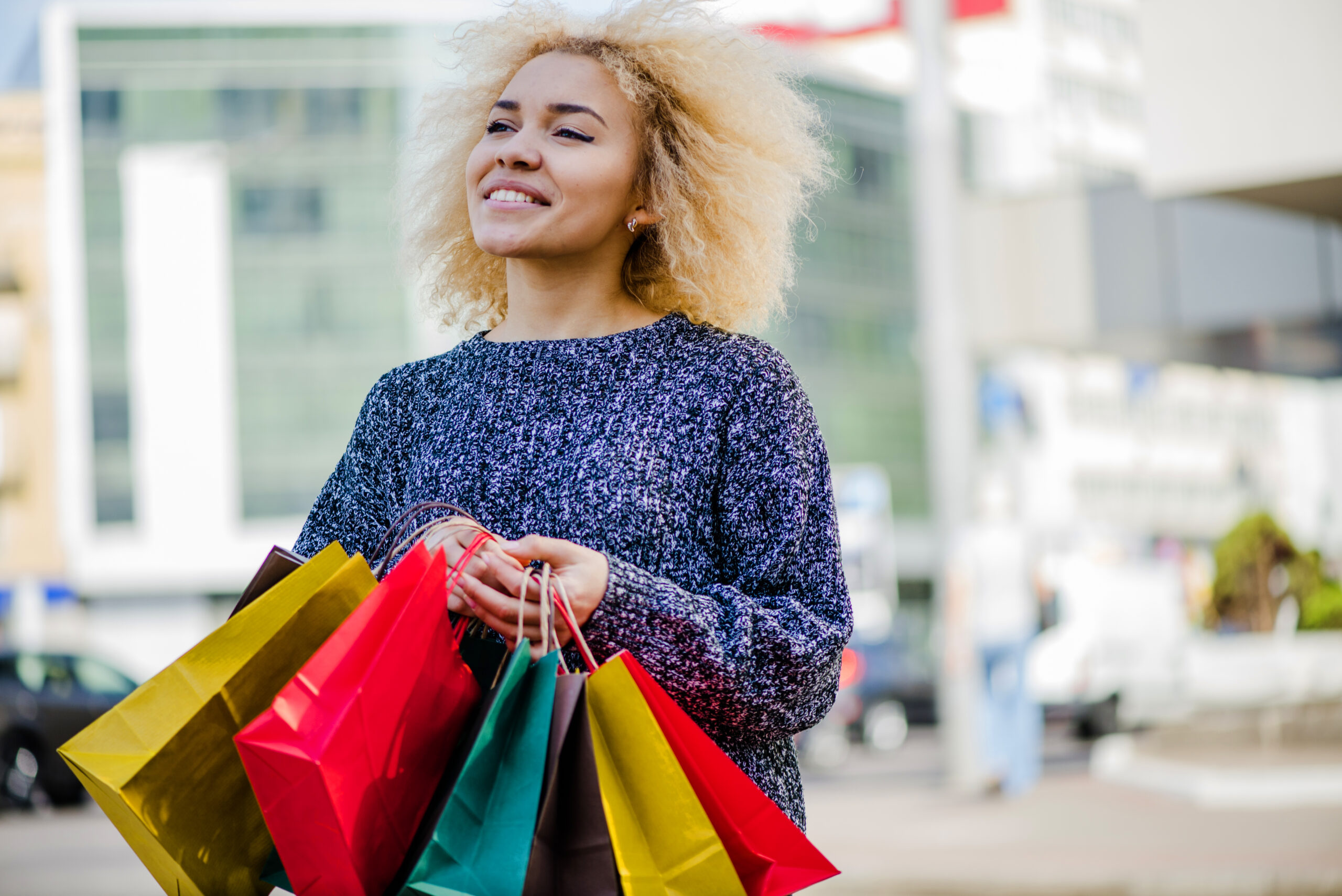 A satisfied customer smiling with her shopping bags